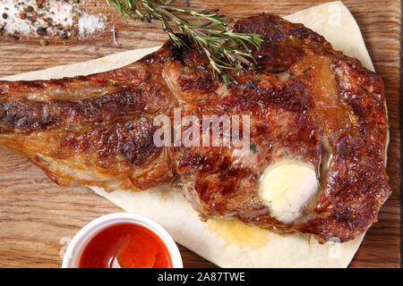 Steak Tomahawk roast on a wooden board with sauce and salt. Stock Photo
