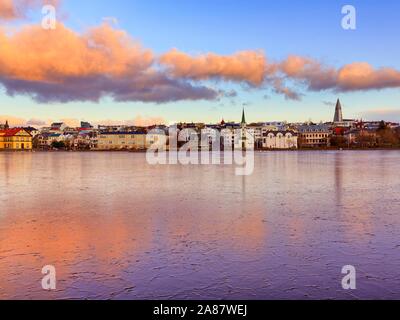 Frozen lake Tjornin in the city centre, cloud reflection at sunset, Reykjavik, Iceland Stock Photo