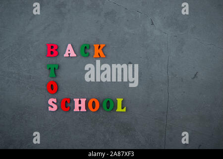 The multicolored back to school word is made of wooden letters on a grey plastered wall background Stock Photo