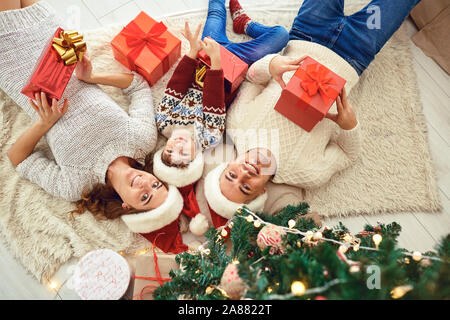 Happy family with Xmas gifts lying on floor Stock Photo
