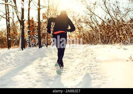 A girl runs through the park in winter at sunset Stock Photo