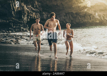 Teenagers running in the water of the ocean at sunset. Group of teen enjoying break of school jumping happy in the sea People enjoy holiday having fun Stock Photo