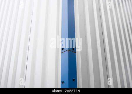 Metal corrugated sheets on a building with a blue metal corners. White aluminium metal corrugated roof or wall sheets on a factories and industrial Stock Photo