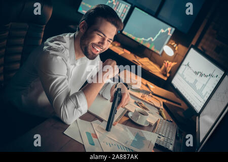 Young male trader at office work concept sitting with gun. Stock Photo
