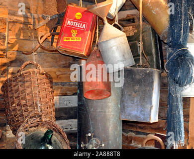 a collection of old oil cans, including Rotella Oil by Shell, hanging in a wooden shed. Stock Photo