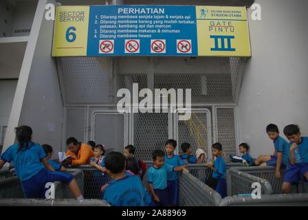 A teacher accompanying elementary students in outdoor learning after sports session outside Gelora Bung Karno Stadium, Jakarta, Indonesia. Stock Photo
