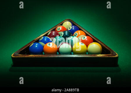 Group of colorful numbered balls in wooden triangle on green table. Horizontal background with equipment for American billiard cue sport game, leisure Stock Photo