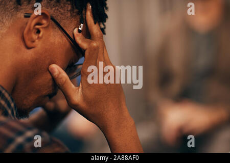 Close-up of African young man holding his head and looking very upset he has problems Stock Photo