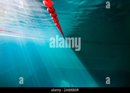 Rays of the sun underwater in a deep pool. Refraction and reflection of rays under water. Underwater photo from the depths of the pool to the surface. Stock Photo