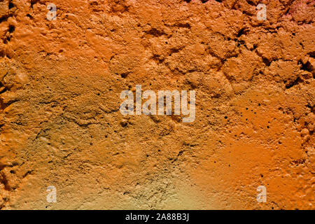 The texture of the unevenly painted wall is light orange. The wall with irregularities and dimples. The background of the orange concrete wall. Stock Photo