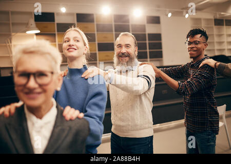 Multiethnic group of people having fun together during therapy lesson they holding each other for shoulders and walking Stock Photo