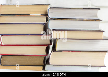 Books for reading in hardcover piles are lying on the table. Stock Photo