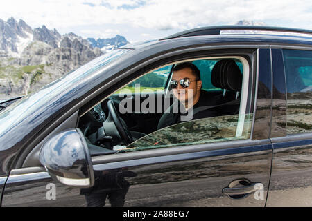 travel, tourism, road trip, transport and people concept - happy man driving car over mountains background Stock Photo