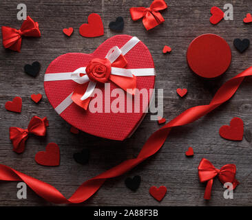 Heart shaped gift box with felt hearts and satin bow on a wooden background. Stock Photo
