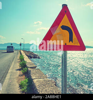 Road sign on corner of road by the sea. Vintage style toned image Stock Photo