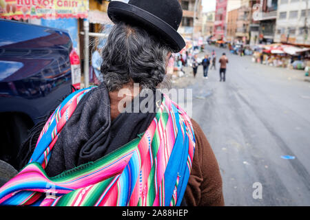 Local woman wearing the classic Bolivian bowler hat on the streets of La Paz, Bolivia Stock Photo