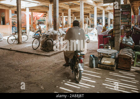 Rissani, Morocco - September 18th, 2019: Man crossing a corridor by motorbike in Risanni bazaar market in Morocco. Stock Photo