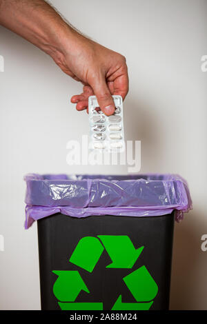 Hand putting expired medicine packages into bin with recycling sign for safe disposal. Person separating dangerous waste. Medical waste management Stock Photo