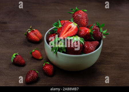 Fresh strawberries in ceramic bowl on dark wooden background. Selective focus. - Image Stock Photo
