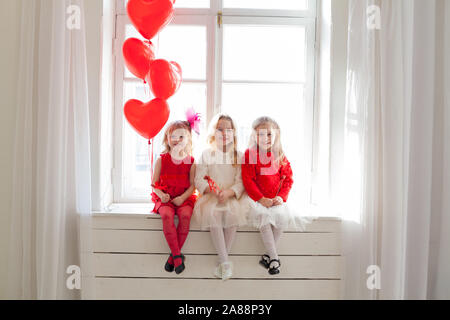 three little girls with red balloons at the party Stock Photo