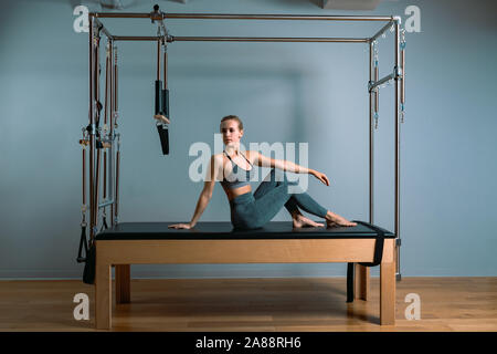 Pilates woman in a Cadillac reformer doing stretching exercises in