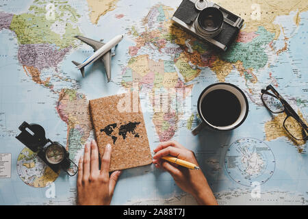 Top view of young woman planning her vacation using world map - Travel influencer looking for the next travel destination Stock Photo