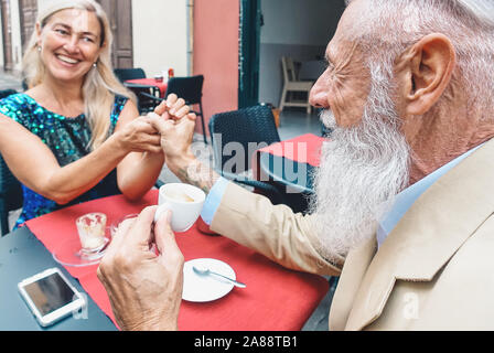 Happy senior couple drinking coffee sitting in a bar - Fashion mature husband and wife looking each other while having break in a restaurant Stock Photo