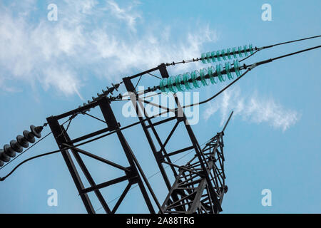 Electric transmission line tower with insulators and conductors. Closeup view on blue sky background. Concept of electric power supply, alternative en Stock Photo