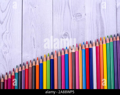 Colored wooden pencils, arranged in the form of a ladder, on a gray and white background. education concept. Stock Photo