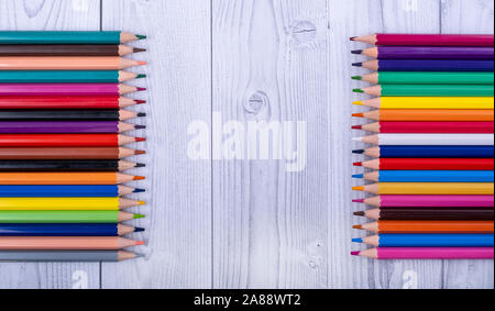 colored wooden pencils, facing each other, on a gray and white wooden background Stock Photo