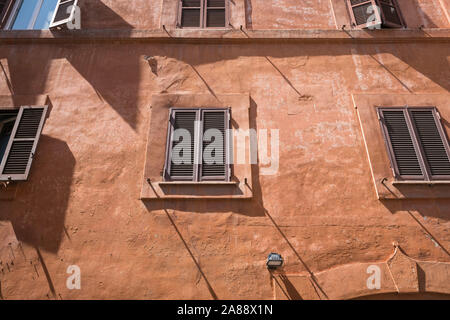 Ancient Roman buildings wall with wooden windows under the sunlight Stock Photo