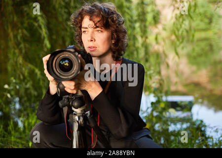 Young photographer with camera and tripod as nature photographer or wildlife photographer Stock Photo