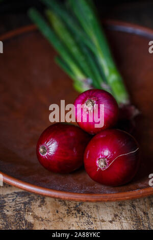 Three red onions on a flat plate Stock Photo