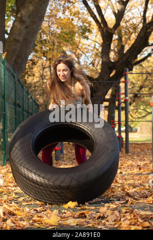 young sports woman does weightlifting on the autumn sports ground Stock Photo