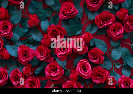 Artificial roses glued to the wall. Beautiful background of their bright red flowers close Stock Photo