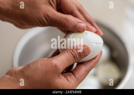 Indian female hands are shelling chicken eggs inappropriately or badly. A women prepares breakfast at home. Egg dish preparation background concept. Stock Photo