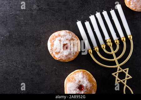 Jewish Hanukkah menorah and sufganiyot donuts on black background. Top view. Copy space Stock Photo