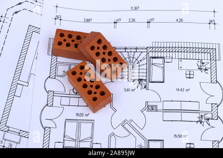 part of a construction plan or blueprint for a residential building with three small brick stones lying on it, architectural background with copy spac Stock Photo