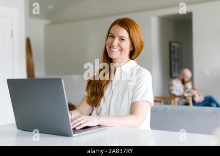 Smiling woman using laptop at home Stock Photo