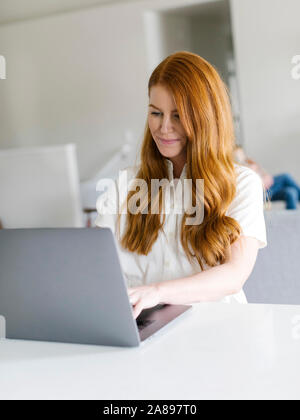 Redheaded woman using laptop at home Stock Photo