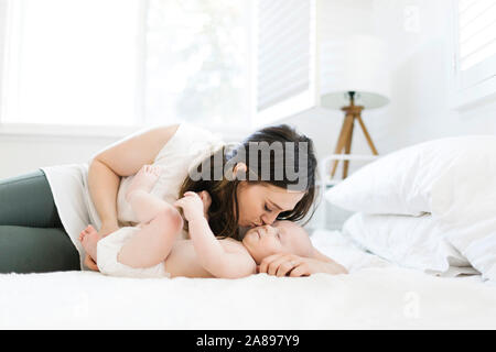 Mother kissing her son's cheek on bed Stock Photo