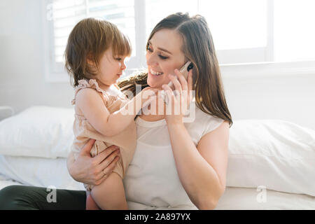 Woman holding daughter while on phone call