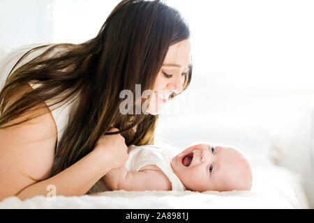 Smiling mother lying with her son on bed Stock Photo