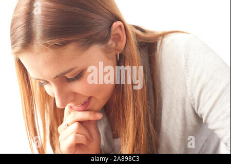 Caucasian teenager girl with long hair looking down at something and smiling Stock Photo