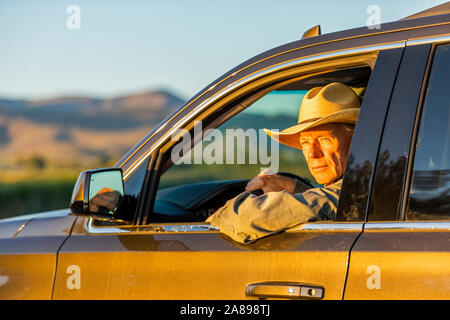 Farmer wearing cowboy hat driving SUV Stock Photo