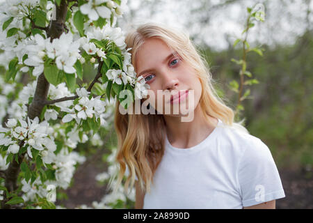 Blond haired young woman among white blossoms Stock Photo