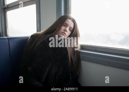 Young woman wearing black fur coat on train Stock Photo - Alamy