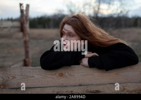 Teenage girl leaning on wooden fence Stock Photo