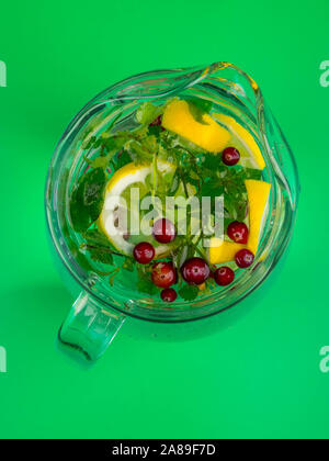Lemonade juice with lime, lemon, mint leaves, cranberries. Fresh summer ice drink, detox water, ice cubes and glass pitcher Stock Photo