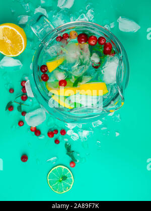 Lemonade juice with lime, lemon, mint leaves, cranberries. Fresh summer ice drink, detox water, ice cubes and glass pitcher Stock Photo